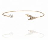 Gold bracelet with pearl and floral design on a white background