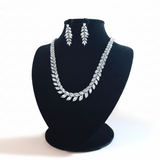 Silver necklace and earrings set on a black mannequin bust against a beige background